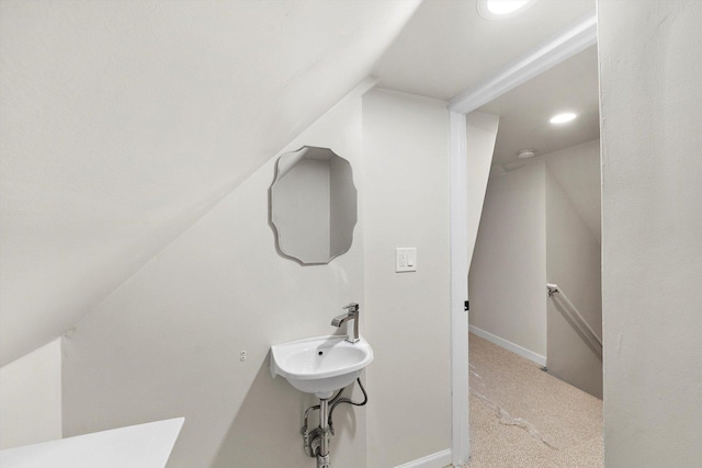 bathroom with lofted ceiling, recessed lighting, baseboards, and a sink