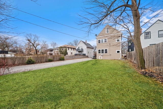 view of yard featuring a residential view, driveway, and a fenced backyard