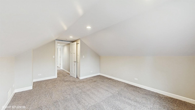 bonus room with vaulted ceiling, light colored carpet, and baseboards