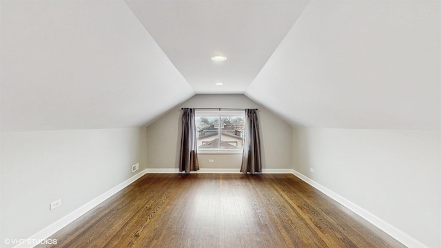 bonus room with dark wood-type flooring, baseboards, and vaulted ceiling