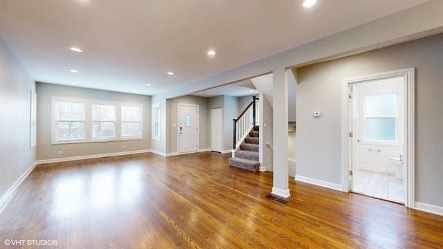 unfurnished living room with visible vents, wood finished floors, recessed lighting, stairway, and baseboards