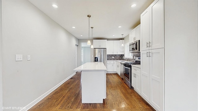 kitchen with a sink, dark wood-style floors, a center island, stainless steel appliances, and decorative backsplash