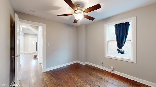 unfurnished room with dark wood-style floors, ceiling fan, and baseboards