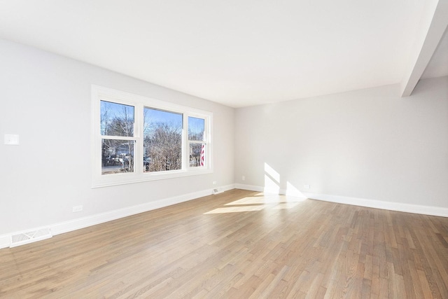 spare room featuring light wood finished floors, baseboards, and visible vents