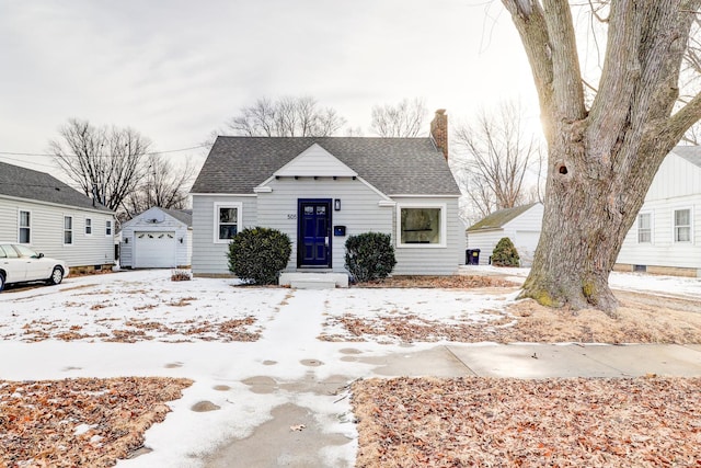 bungalow with a garage, an outbuilding, a shingled roof, and a chimney