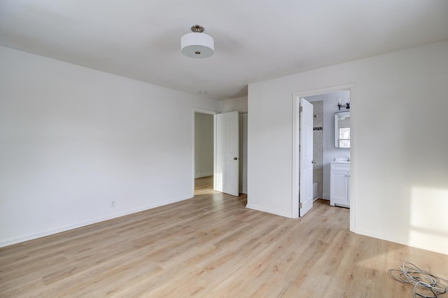 unfurnished bedroom featuring ensuite bathroom, light wood finished floors, and baseboards