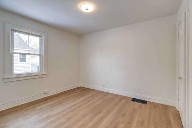 spare room featuring baseboards, visible vents, and light wood finished floors