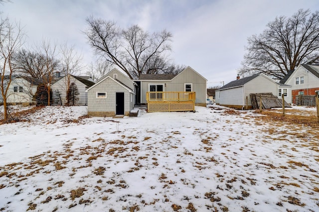 snow covered rear of property featuring an outbuilding and a wooden deck