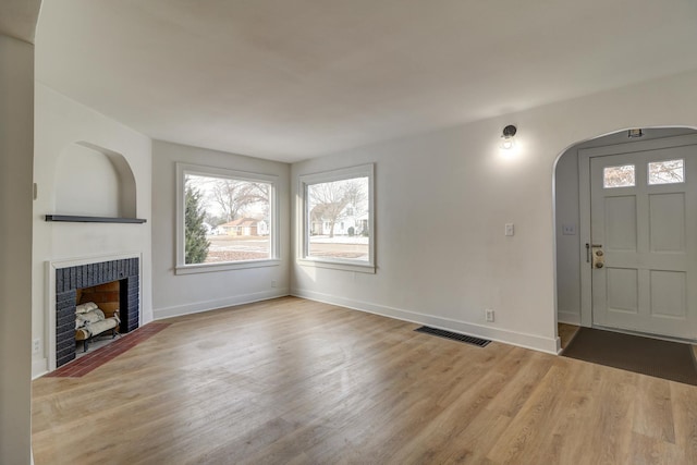 unfurnished living room featuring a fireplace, wood finished floors, visible vents, and baseboards