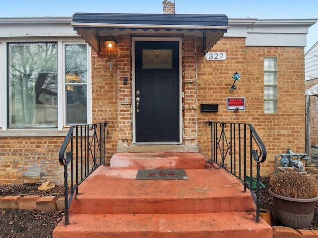 property entrance with brick siding and a chimney