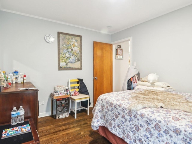 bedroom featuring baseboards, wood finished floors, and crown molding