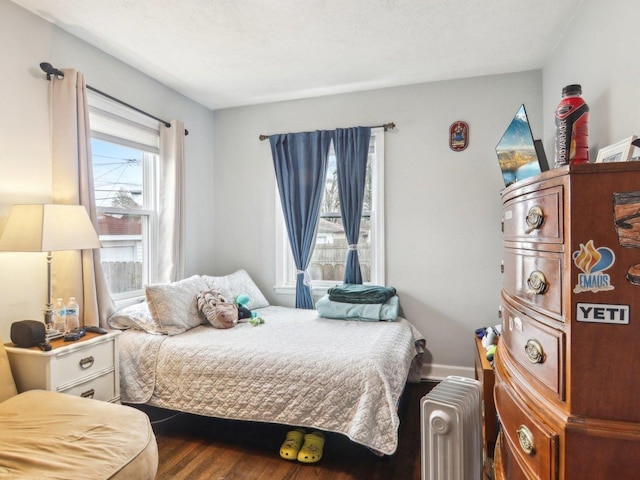 bedroom with radiator, baseboards, and wood finished floors