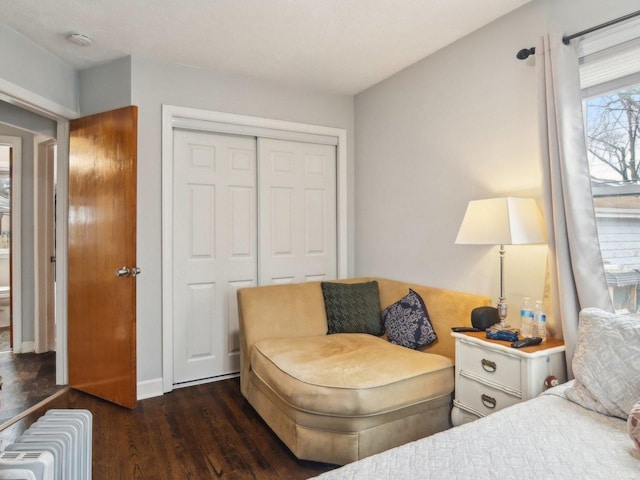 bedroom featuring radiator, a closet, baseboards, and wood finished floors