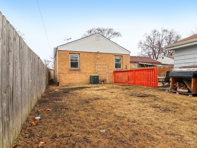 back of property featuring central AC, brick siding, and a fenced backyard