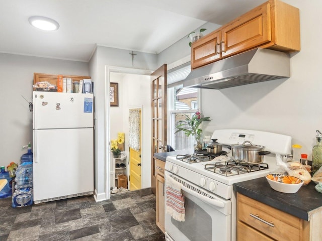 kitchen with dark countertops, white appliances, stone finish floor, and under cabinet range hood