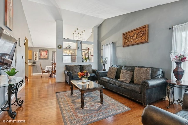 living area with high vaulted ceiling, wood finished floors, and baseboards