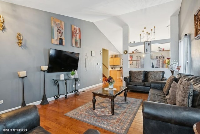 living room featuring high vaulted ceiling, baseboards, and wood finished floors