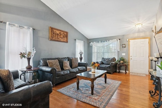 living area with vaulted ceiling, light wood-style flooring, and baseboards