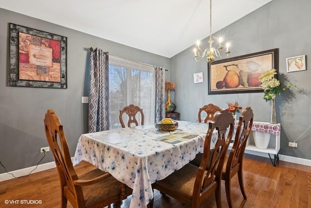 dining area featuring lofted ceiling, an inviting chandelier, wood finished floors, and baseboards