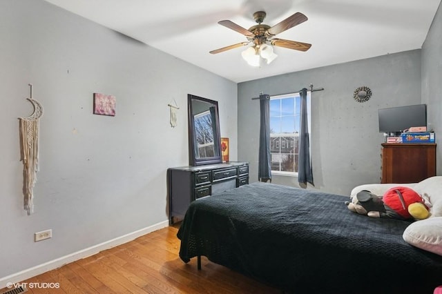 bedroom with a ceiling fan, baseboards, and light wood finished floors