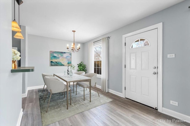 unfurnished dining area featuring a notable chandelier, baseboards, and wood finished floors