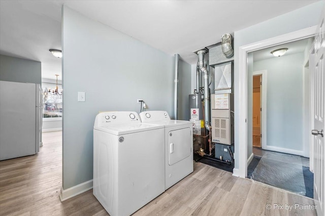 clothes washing area with baseboards, washing machine and clothes dryer, laundry area, water heater, and light wood-style floors