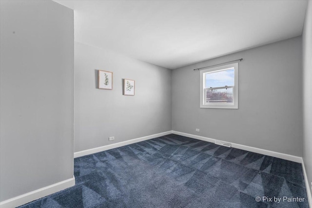 unfurnished room featuring dark colored carpet and baseboards