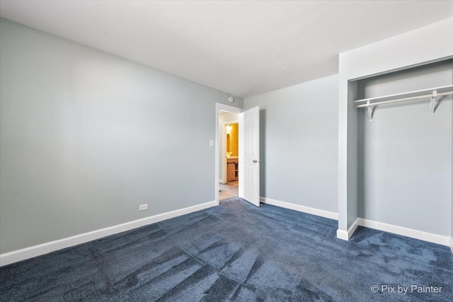 unfurnished bedroom with a closet, baseboards, and dark carpet