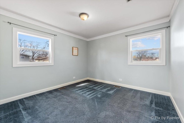 spare room featuring a healthy amount of sunlight, crown molding, baseboards, and dark colored carpet