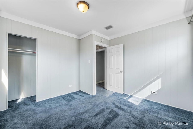 unfurnished bedroom featuring a closet, carpet flooring, visible vents, and ornamental molding