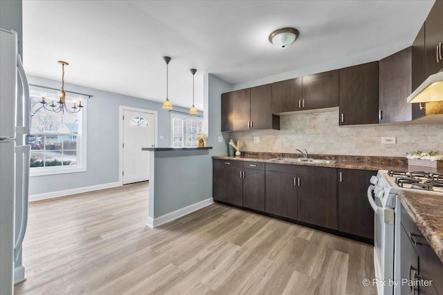 kitchen featuring decorative backsplash, gas range gas stove, dark brown cabinets, and freestanding refrigerator