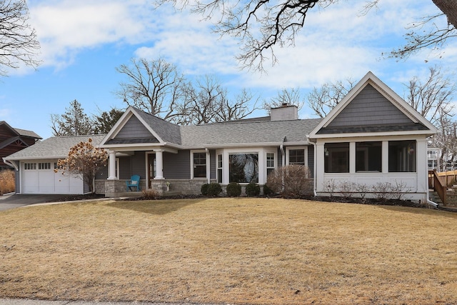 view of front of property featuring roof with shingles, a chimney, an attached garage, a front yard, and driveway