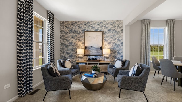 living area with wallpapered walls, visible vents, baseboards, and carpet flooring