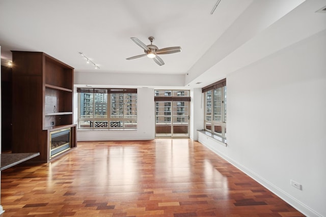 unfurnished living room with visible vents, baseboards, a ceiling fan, wood finished floors, and track lighting