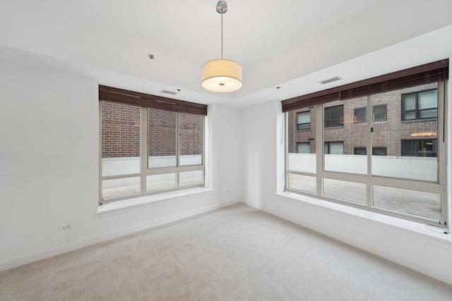 carpeted empty room featuring a raised ceiling, visible vents, and baseboards