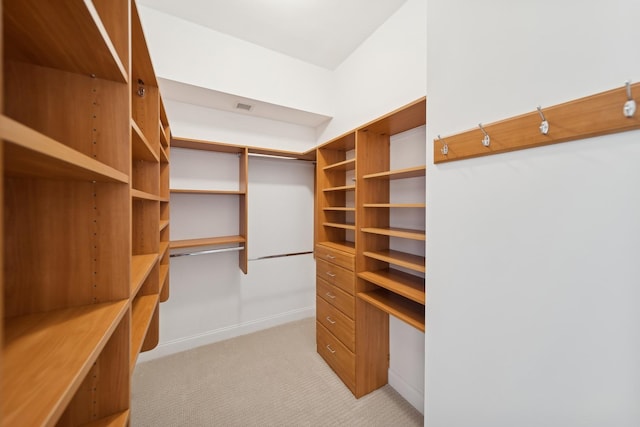 walk in closet featuring built in desk, visible vents, and light colored carpet