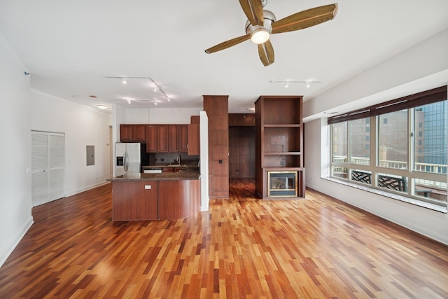 kitchen featuring light wood finished floors, stainless steel fridge, electric panel, dark countertops, and a peninsula