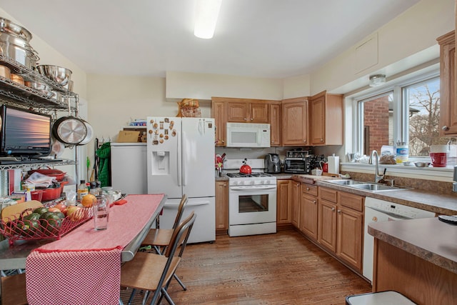 kitchen with white appliances, light wood-style flooring, washer / clothes dryer, and a sink