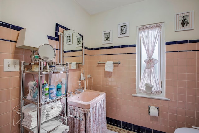 bathroom featuring a sink, toilet, and tile walls