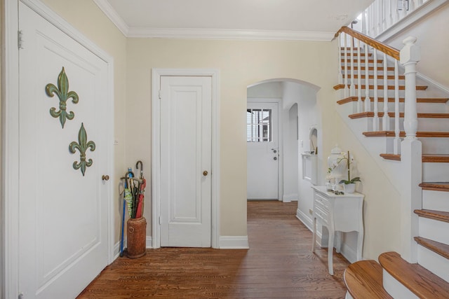 entryway with baseboards, arched walkways, wood finished floors, stairs, and crown molding