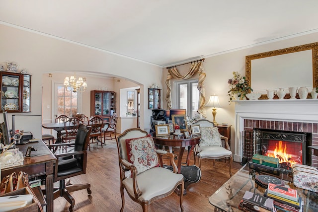 living room with a fireplace, arched walkways, wood finished floors, and ornamental molding