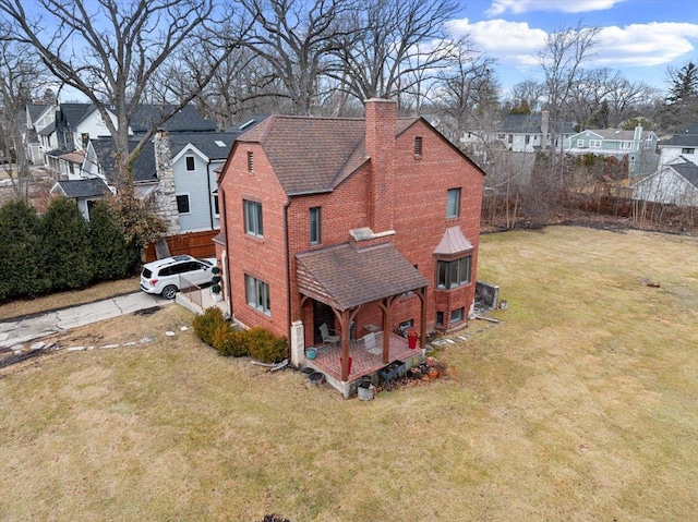 exterior space featuring a yard, a chimney, a residential view, and brick siding