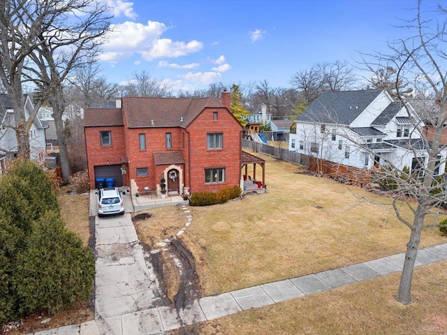 view of front of home featuring brick siding, concrete driveway, a chimney, fence, and a front yard