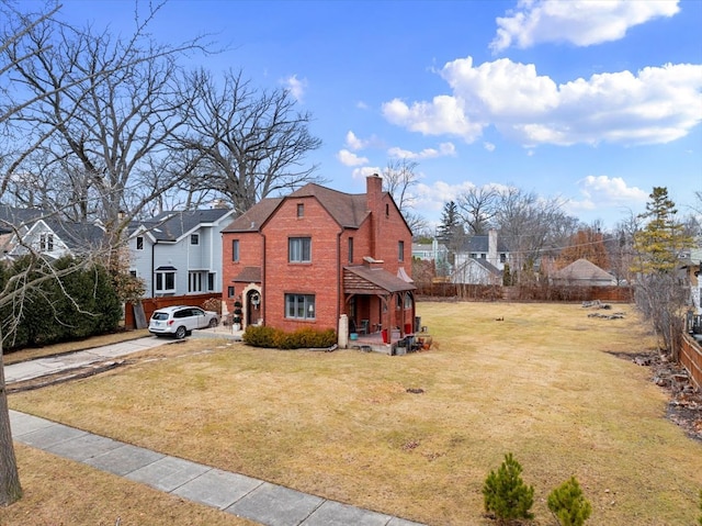 view of front of home with a front yard, brick siding, a residential view, and a chimney