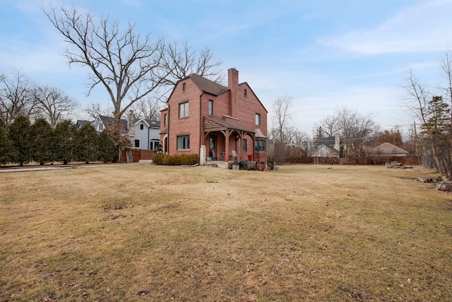 exterior space with a yard, a chimney, and brick siding