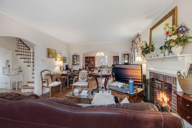 living room with arched walkways, a fireplace, stairway, ornamental molding, and wood finished floors