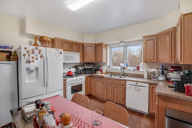 kitchen with white appliances, a sink, and wood finished floors