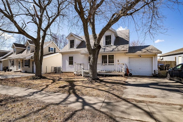 cape cod home featuring a garage, covered porch, and driveway