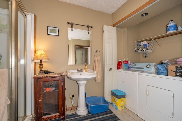 bathroom with tile patterned flooring, independent washer and dryer, and a textured ceiling