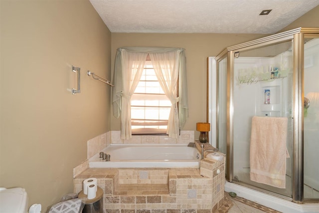 full bathroom with a textured ceiling, a stall shower, and a bath